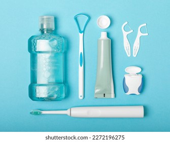 Electronic ultrasonic toothbrush, mouthwash, floss, tongue cleaner and toothpaste on blue textured background. Items for dental care and caries prevention in the bathroom. Dentistry concept. Copy spac - Shutterstock ID 2272196275