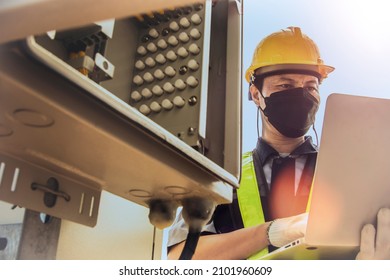 Electronic worker man wearing mask, skilled control system, control cabinet, station, signal tower. Telecom uses a laptop to check the telecommunication circuit board system.