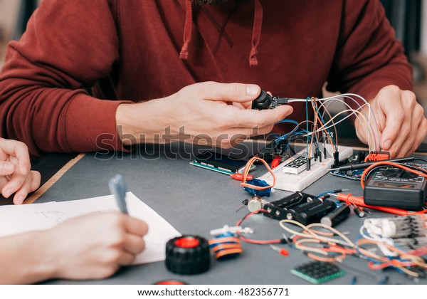 Electronics construction in laboratory.\
Unrecognizable engineer connecting components and cables to\
breadboard, educational\
experiment