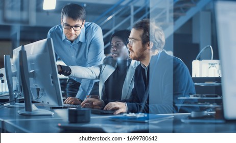 Electronics Development Engineer Working on Computer, Talks with Project Manager, Another Specialist Joins Discussion. Team of Professionals Use CAD Software for Modern Industrial Engineering Design. - Powered by Shutterstock