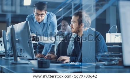 Electronics Development Engineer Working on Computer, Talks with Project Manager, Another Specialist Joins Discussion. Team of Professionals Use CAD Software for Modern Industrial Engineering Design.