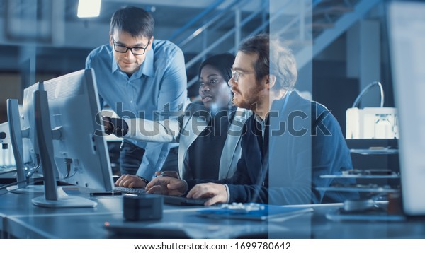 Electronics Development Engineer Working on\
Computer, Talks with Project Manager, Another Specialist Joins\
Discussion. Team of Professionals Use CAD Software for Modern\
Industrial Engineering\
Design.