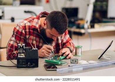 Electronics engineer man repairing computer part in service center. Fixing service in lab. Concentrated while working.Electronics repair service. It technician soldering circuit board in a workshop. - Shutterstock ID 2228511491