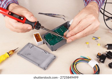 Electronics engineer solder electrical components of device at the service workplace.