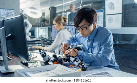 Electronics Engineer Works With Robot Checking Voltage And Program Response Time. Computer Science Research Laboratory With Specialists Working.