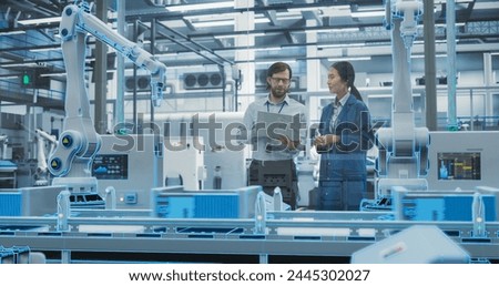 Electronics Factory Digitalization: Automated Robot Arm Assembly Line Manufacturing Equipment. Managers Discussing Work while Futuristic AI Computer Vision Analyzing, Scanning Production Line