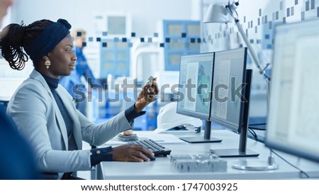 Electronics Factory: Female Electrical Engineer Holds PCB Prototype, Works on Computer, uses CAD Software to Develop Microchips, Semiconductor and Telecommunications Equipment. Manufacturing Facility