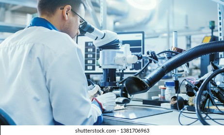 Electronics Factory Worker in White Work Coat is Soldering a Printed Circuit Board Through a Digital Microscope. High Tech Factory Facility. - Shutterstock ID 1381706963