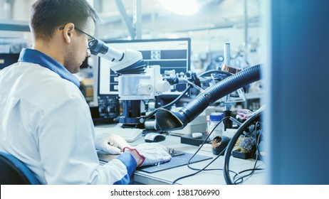 Electronics Factory Worker in White Work Coat Inspects a Printed Circuit Board Through a Digital Microscope. High Tech Factory Facility. - Shutterstock ID 1381706990