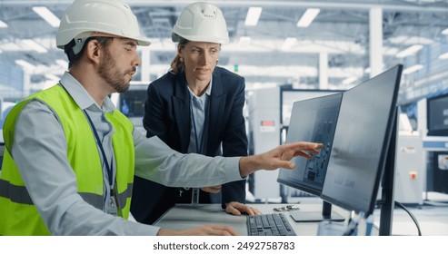 Electronics Research and Development Facility: Caucasian Female Manager Consults Male Engineer. Professionals Wear Hardhats And Design Microchips And Semiconductors On Computer At Modern Factory. - Powered by Shutterstock