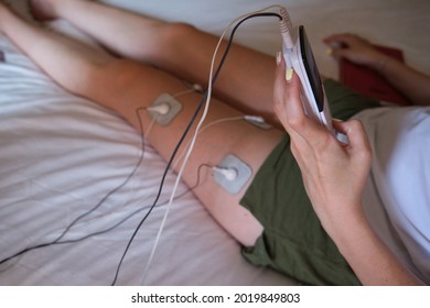 electrostimulation treatment at home, electrodes on the leg of an unrecognizable woman, getting a treatment of tens, ems or massages to improve muscle health and improve blood circulation. recovery