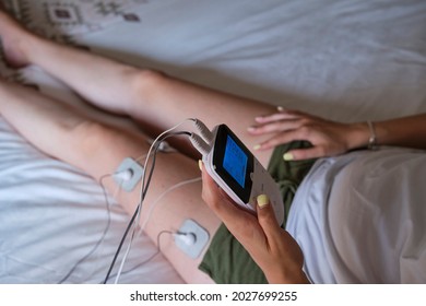 electrostimulation treatment at home, electrodes on the leg of an unrecognizable woman, getting a treatment of tens, ems or massages to improve muscle health and improve blood circulation.