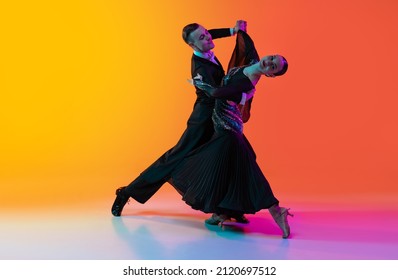 Elegance  Full  length portrait young beautiful man   woman dancing ballroom dance isolated over gradient orange pink background in neon light  Concept art  beauty  grace  action  emotions 