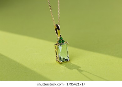 Elegance gold pendant necklace with baguette cut beryl gem and emeralds on bright green background. Fashion jewelry with natural gemstone - Shutterstock ID 1735421717