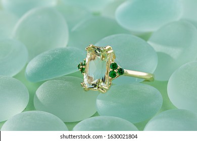 Elegance gold ring with beryl gem and emerald on pastel blue backround. Fashion gold jewelry with gemstone - Shutterstock ID 1630021804