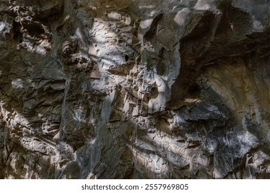 Elegance of The intricate natural light and shadow on surface of stone wall. Pattern of granite on the mountains that erode naturally,The sunlight shining through down to Limestone wall.Space for text - Powered by Shutterstock