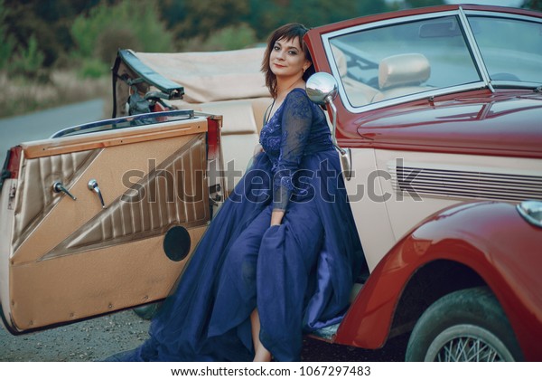 Elegance\
lady in a blue dress sitting in a red retro\
car