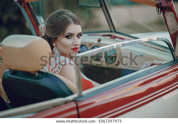 Elegance\
lady in a red dress sitting in a red retro\
car