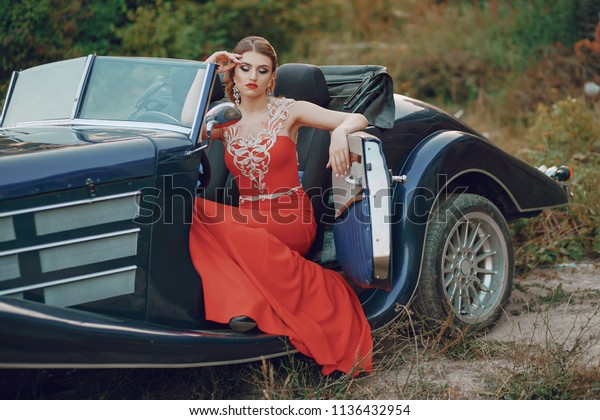 Elegance\
lady in a red dress sitting in a retro blue\
car