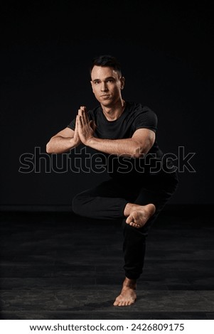 Elegance personified, a charming young man in black clothing demonstrates his commitment to self-care and well-being through the art of yoga, embodying balance and grace.