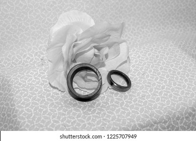 The elegance and romance of a flower and Damascus wedding bands in a black and white image.