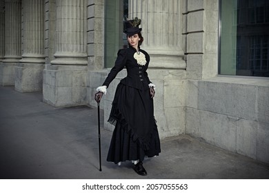 An elegant 19th century lady strolls down a city street. History and Fashion of the late 19th - early 20th century. Full length portrait.