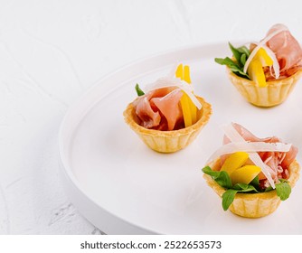 Elegant appetizers with prosciutto, melon, and arugula served on a sleek white dish for fine dining - Powered by Shutterstock