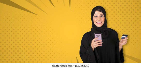 Elegant Arab Woman In Abaya Standing Yellow Background Holding Mobile Phone And Debit Card. Businesswoman Paying With Credit Card, Online Shopping Concept Using Mobile.