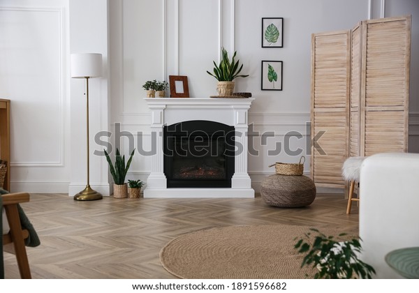 Elegant\
artificial fireplace in room. Interior\
design