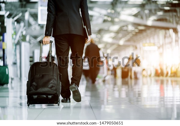 Elegant asian businessman checking email on mobile
phone while walking with suitcase inside airport, experienced male
employer using cell telephone while waiting for taxi car coming
before work travel