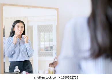 Elegant Asian Businesswoman Buttoning Up Shirt In Front Of Mirror Getting Ready For Work