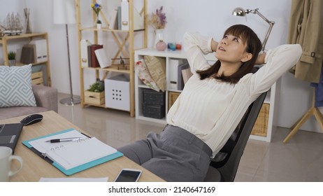 elegant asian woman ceo relaxed sitting on swivel chair and staring at office ceiling while thinking about her work plan.