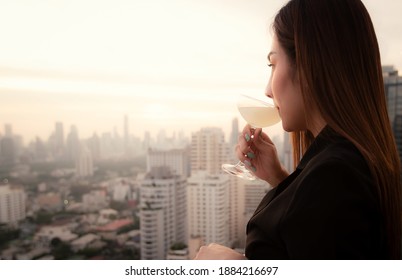 Elegant Asian woman drinking cocktail at rooftop bar restaurant of hotel. Bangkok, Thailand, Asia 