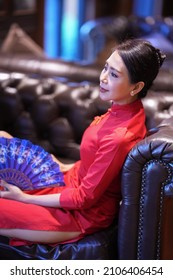Elegant Asian woman wear red cheongsam in the restaurant and a bar, leisure activities.