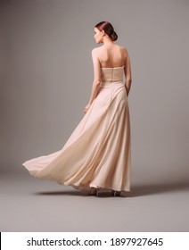 Elegant backless moscato dress. Beautiful pink chiffon evening gown. Studio portrait of young ginger woman. Transformer dress idea for an event. Bridesmaid dresses. - Shutterstock ID 1897927645