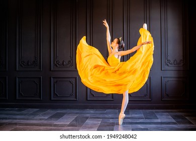 elegant ballerina in pointe shoes dances in a long yellow skirt