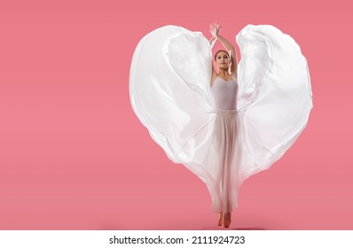 elegant ballerina in pointe shoes dancing in a long white skirt developing in the shape of a heart on a pink background - Powered by Shutterstock