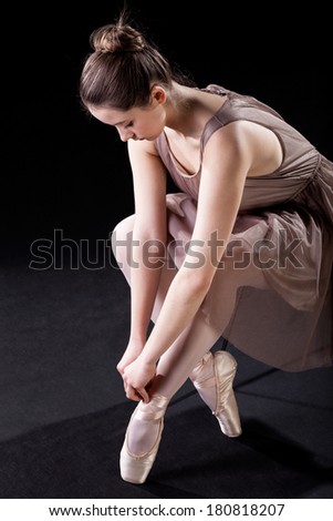 An elegant ballet dancer tying her pointe shoes