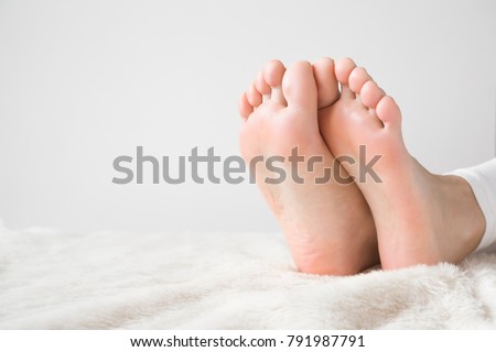 Elegant bare feet. Beautiful groomed woman's feet on the fluffy blanket. Cares about clean and soft legs skin. Lying and enjoying rest.