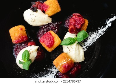 Elegant black plate dessert featuring homemade biscuits, fresh raspberries, berry compote, herb garnish, and powdered sugar. Perfect for brunch, breakfast, or special occasions. Close up - Shutterstock ID 2254786737