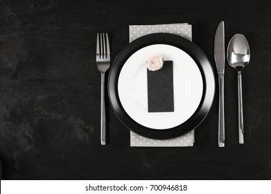 Elegant Black And White Table Setting: Plates, Gray Polka Dot Napkin, Blank Label With Rose And Silverware. Top View Point.