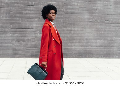 Elegant black woman looking at the camera while walking on the street. Urban lifestyle concept.