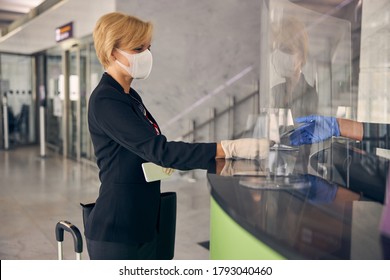 Elegant Blonde Woman In Medical Mask Giving Boarding Pass To Airport Worker Before The Flight