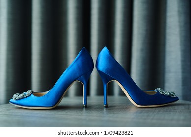 Elegant blue and silver high heel shoes for women sitting on a textured surgace.