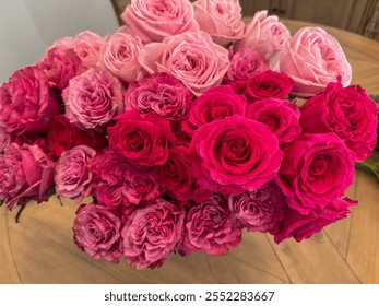 An elegant bouquet featuring vibrant red and soft pink roses, showcasing lush blooms and intricate petal layers, placed on a wooden surface for a romantic and sophisticated aesthetic. - Powered by Shutterstock