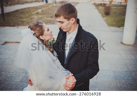 Elegant bride and groom posing together outdoors on a wedding day.
