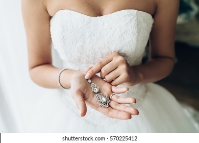 Elegant bride holding silver earrings. Tender hands with jewelry.