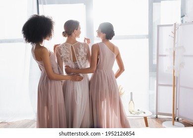 elegant bridesmaids hugging young bride on sunny morning at home