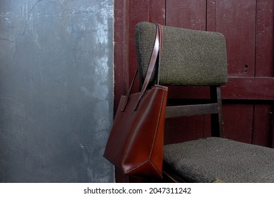 Elegant brown leather tote shoulder bag hanging on old chair