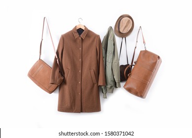 Elegant Brown Long Coat And Jacket On Hanging With Three Brown Handbag ,hat Isolated On White Background
